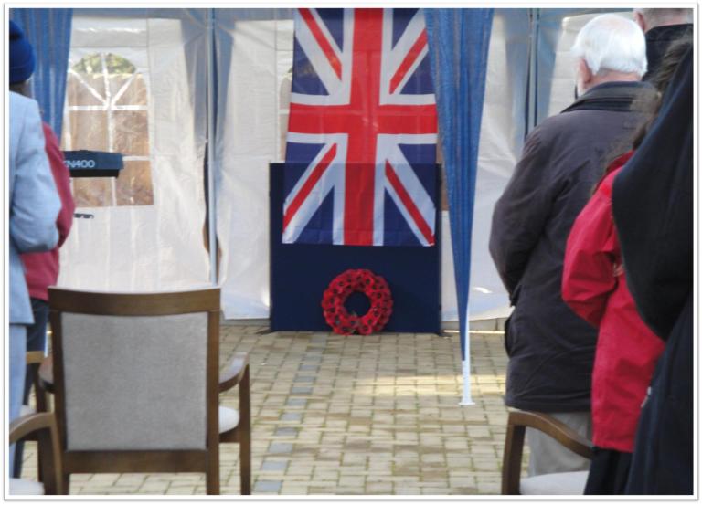 chairs facing a british flag with people facing towards it with their heads down