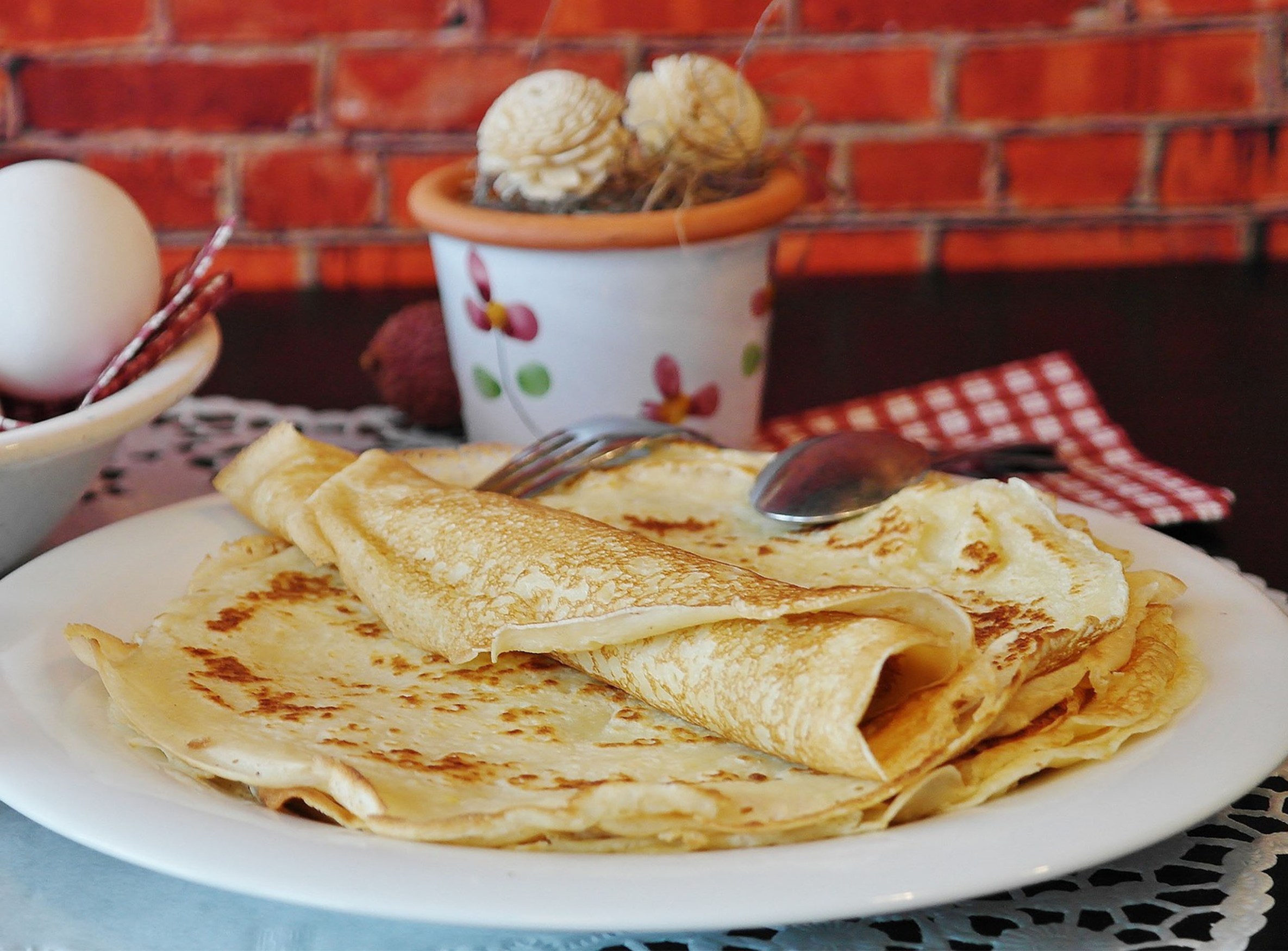 a plate with thin pancakes and a small tub with ice cream behind it
