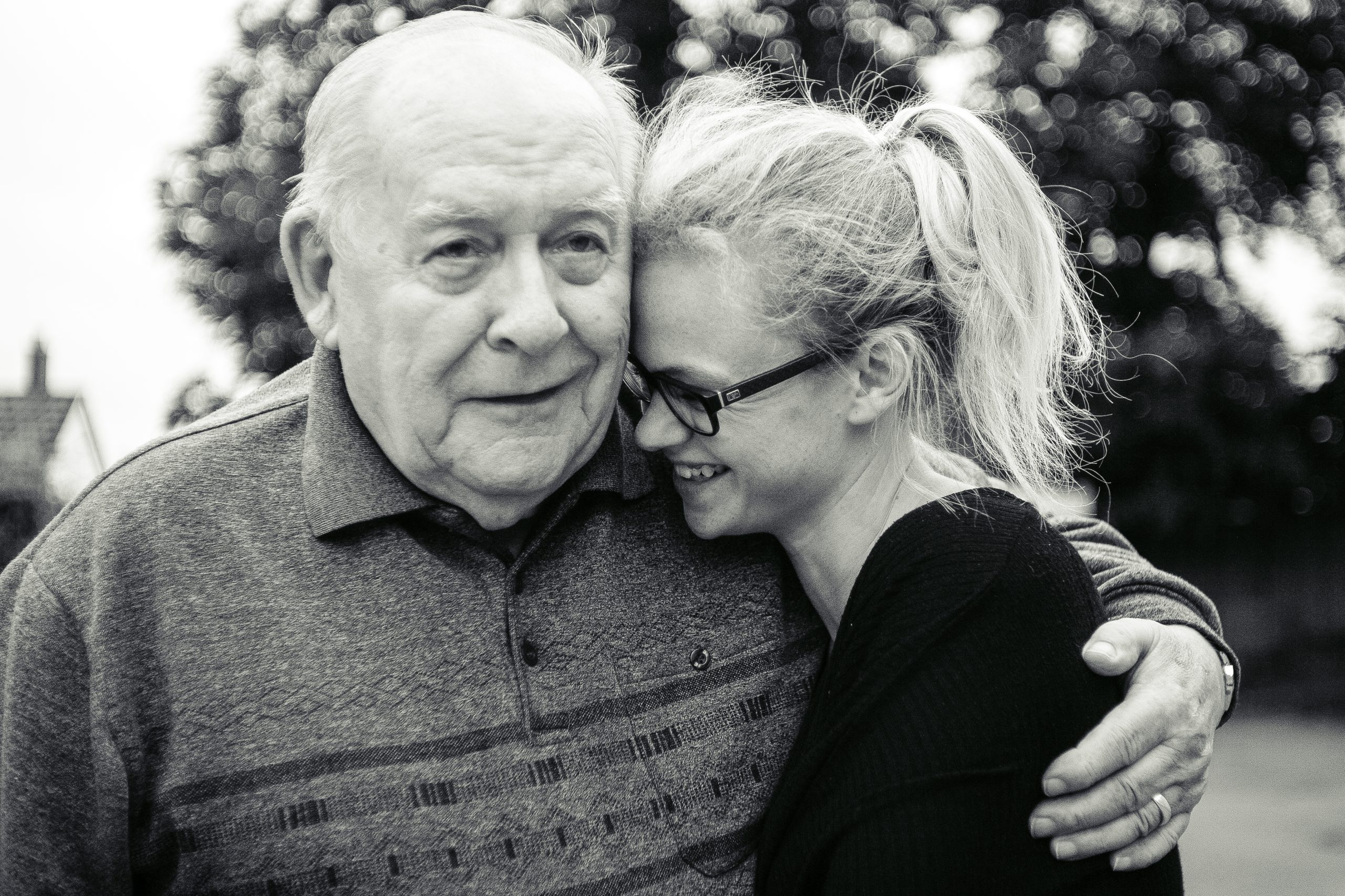 a black and white image of a elderly man hugging a youger woman
