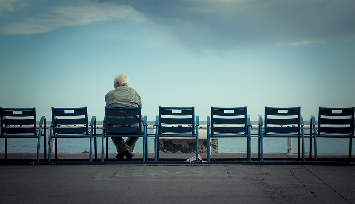 7 chairs face away from the camera with one man sat down in one of the chairs looking at the backdrop